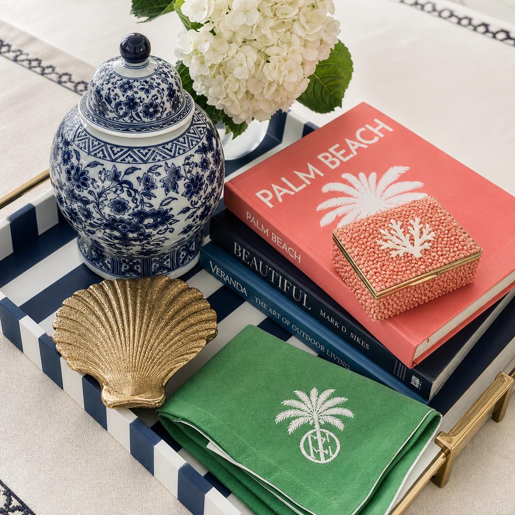 Curated preppy coastal home goods flat lay with ginger jar, brass shell, and coral box